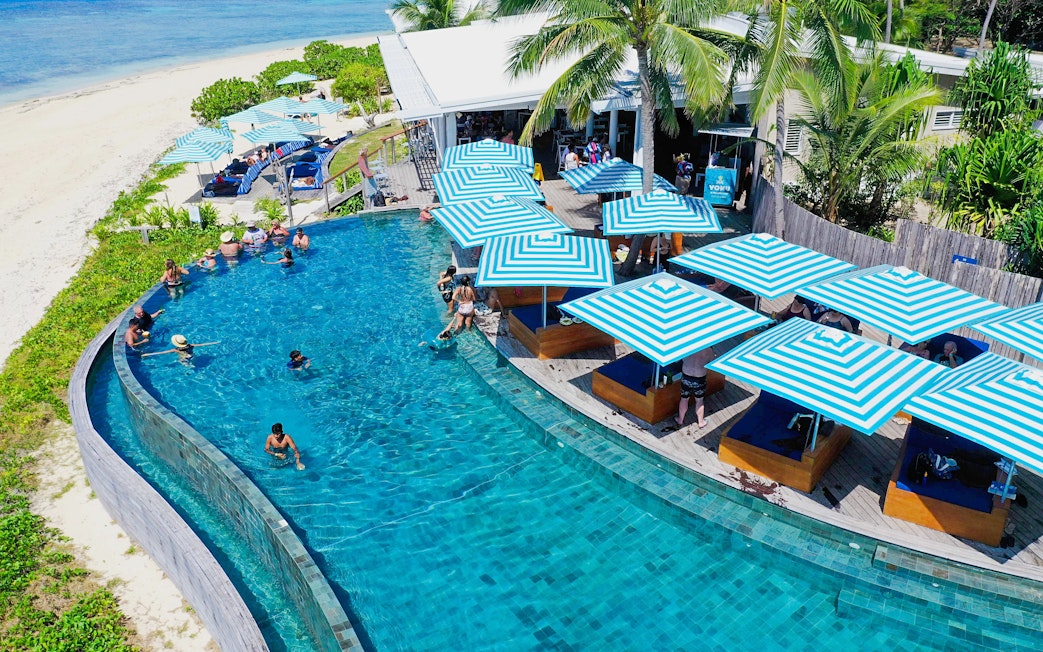 Aerial view of pool with striped umbrellas at Malamala Beach Club, Fiji.