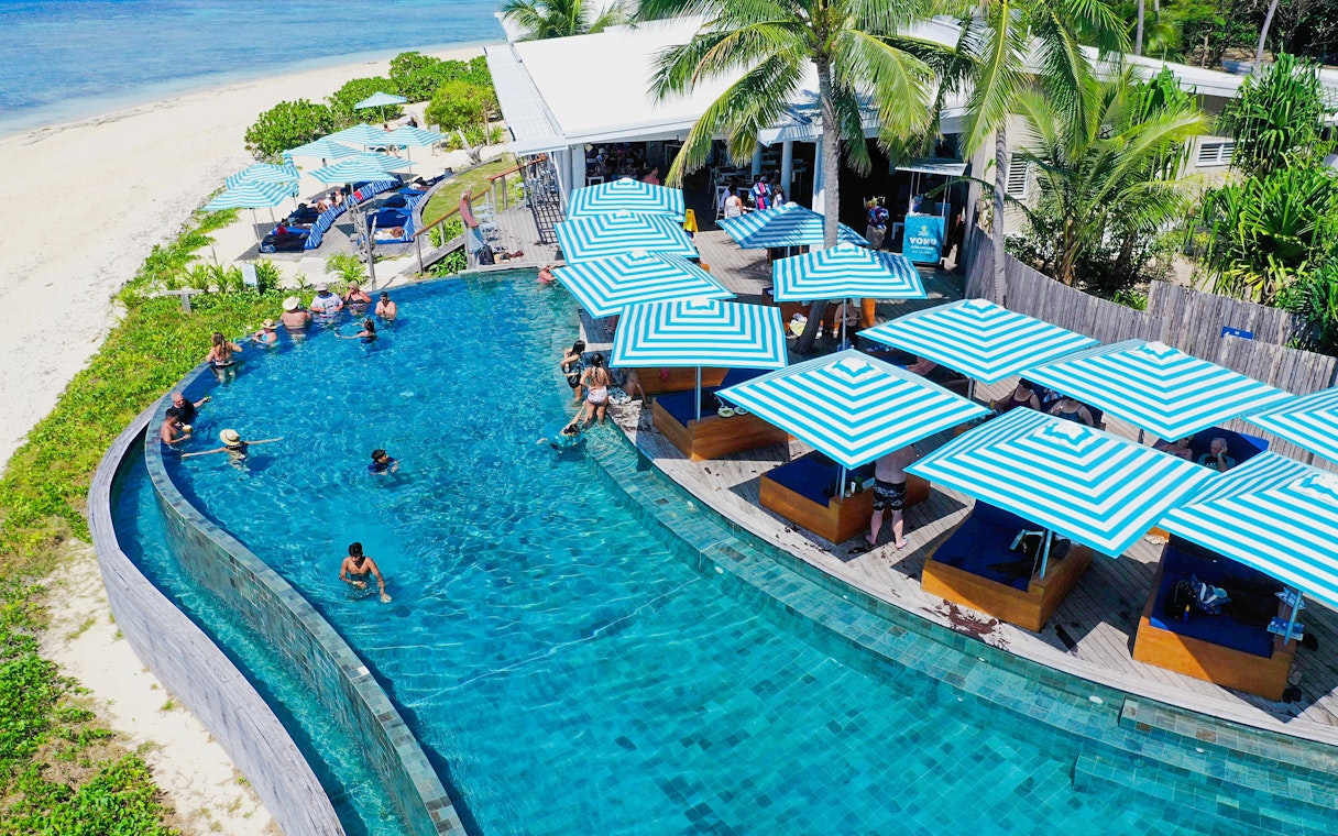 Aerial view of pool with striped umbrellas at Malamala Beach Club, Fiji.