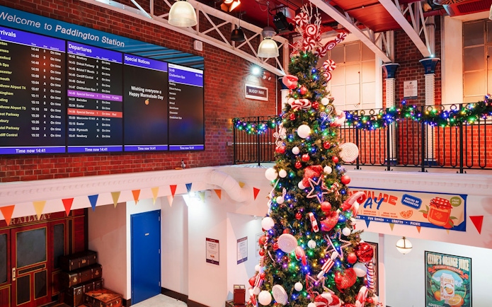 Christmas tree at Paddington Station, London, decorated with lights and ornaments, festive atmosphere.