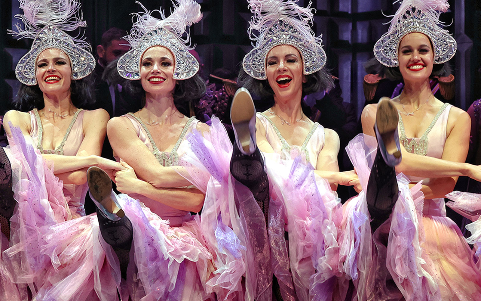 Dancers performing in The Merry Widow, Sydney, wearing ornate hats and pink costumes.