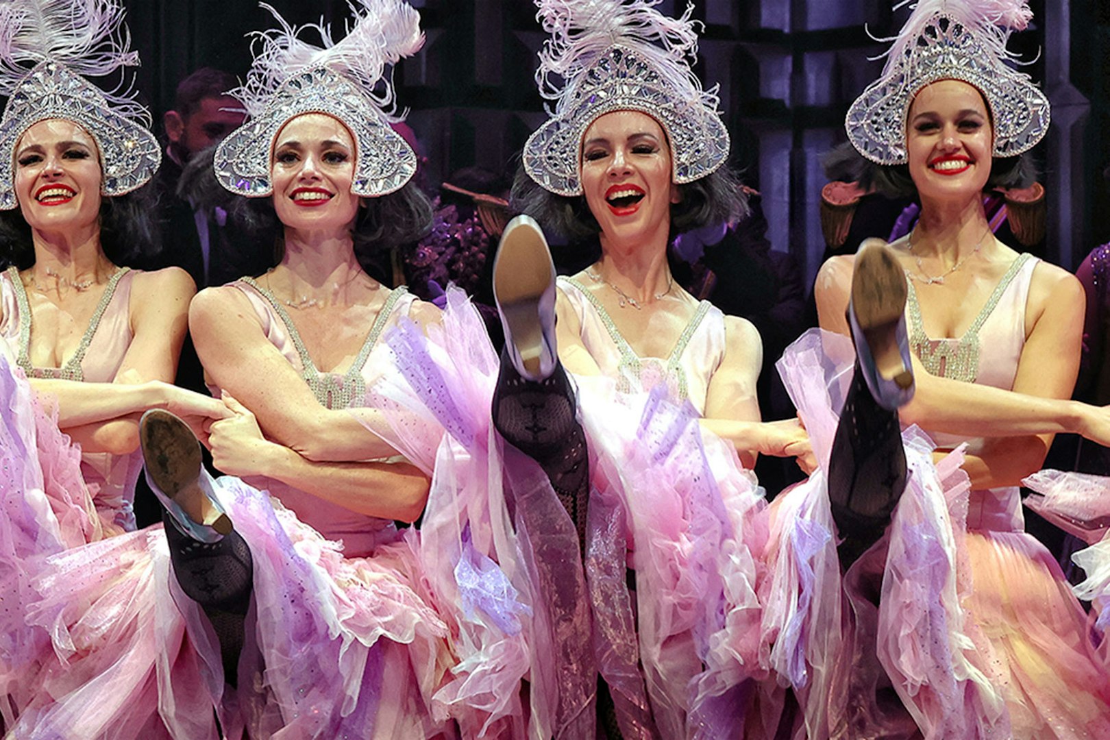 Dancers performing in The Merry Widow, Sydney, wearing ornate hats and pink costumes.