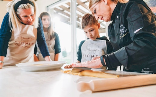 Fresh pasta making class with chef guiding participants in rolling dough.