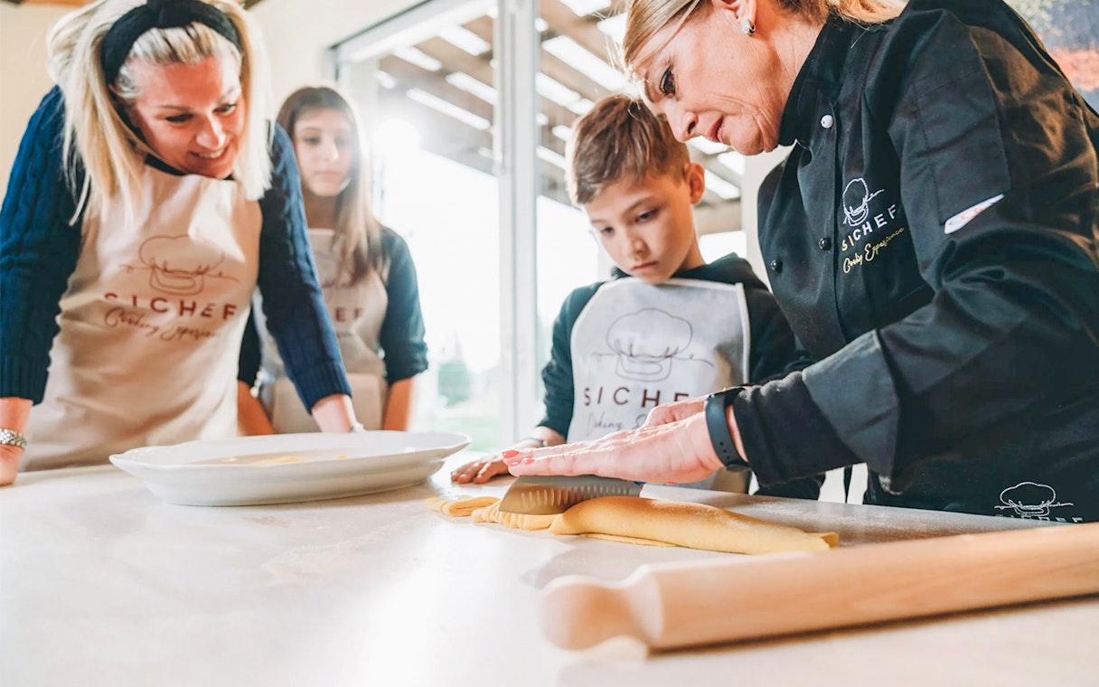 Fresh pasta making class with chef guiding participants in rolling dough.