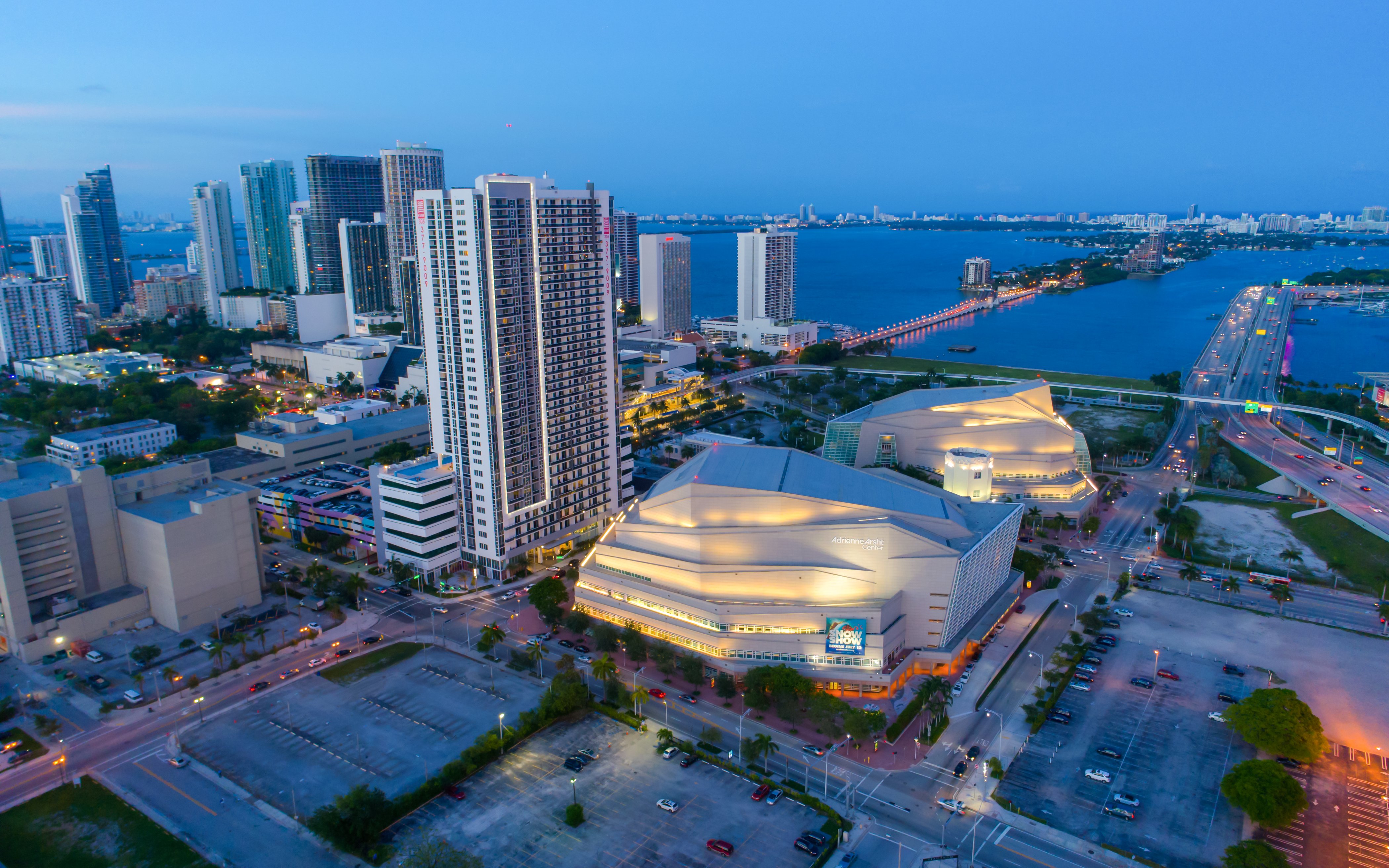 Aerial view of the Adrienne Arsht Center in Miami with surrounding cityscape and bay.