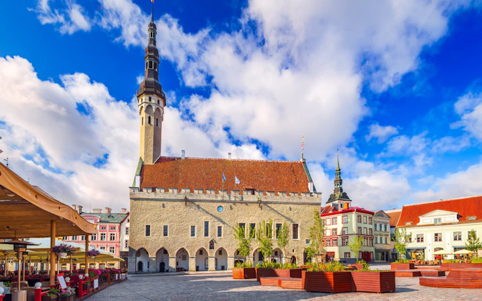 Raekoja Plats with Tallinn Old Town Hall under a blue sky in Estonia.