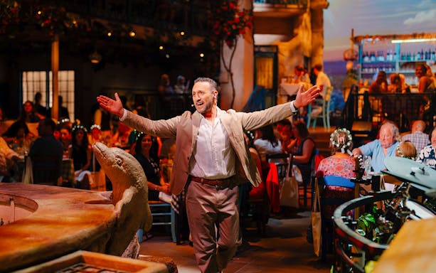 Performer engaging audience at Mamma Mia! The Party event with Mediterranean decor.