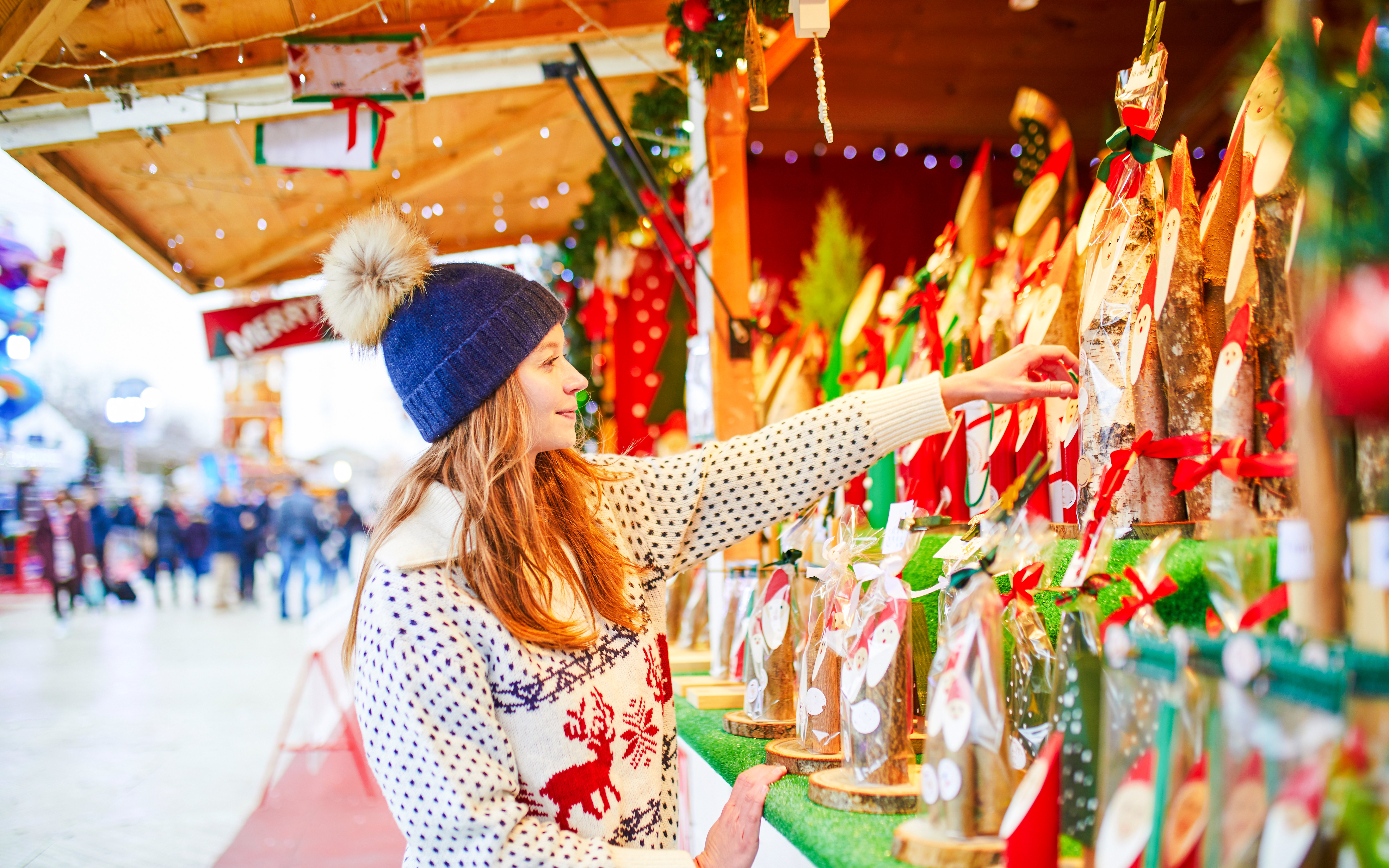 Person selecting gifts at a Paris Christmas market stall.