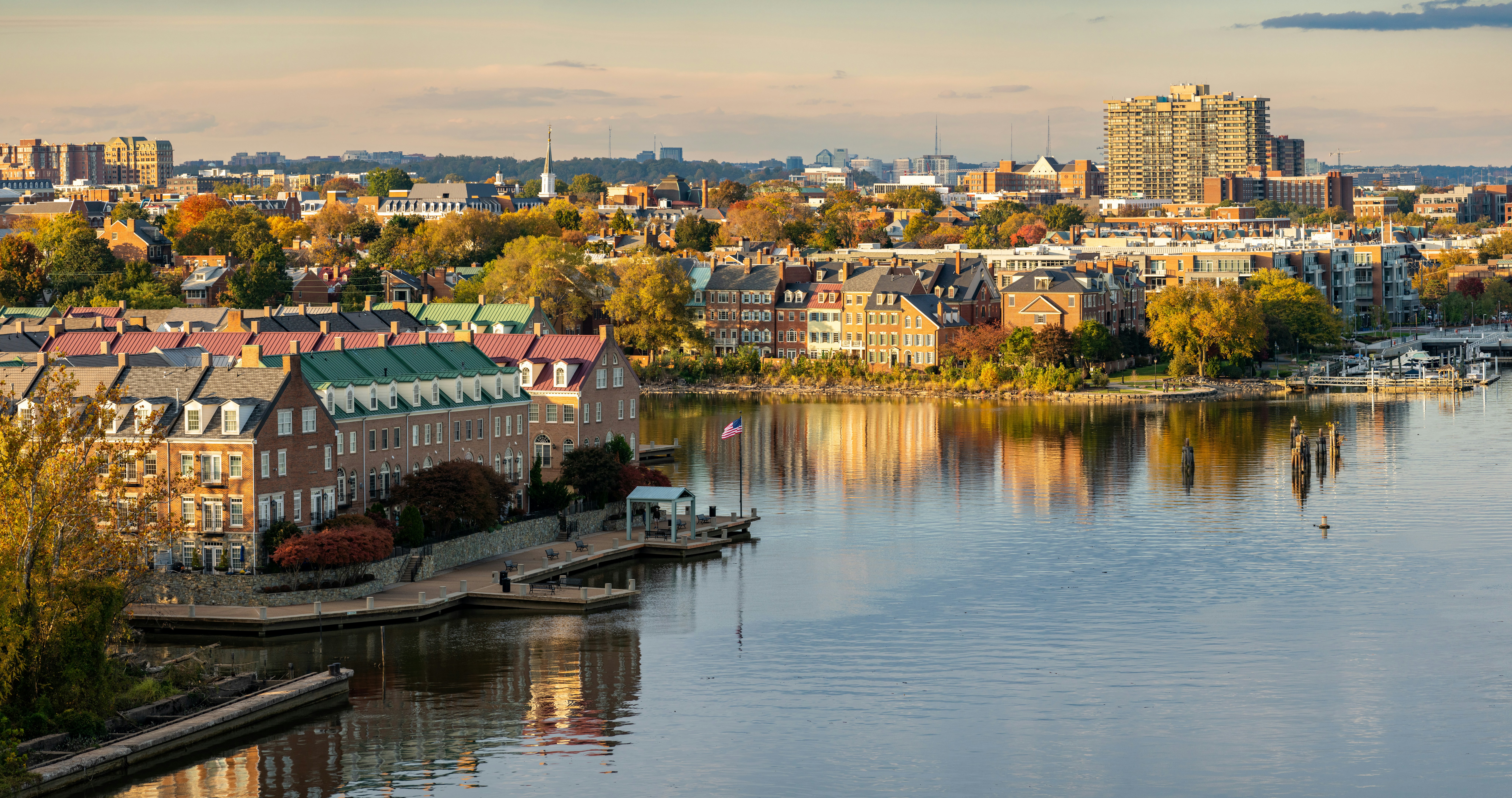 Alexandria waterfront skyline with historic buildings and autumn trees reflecting in the water.