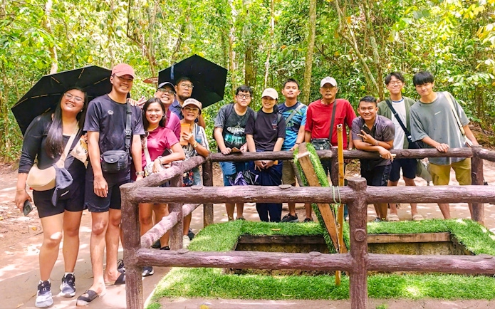 Tourists exploring booby trap at Cu Chi tunnels, Vietnam.