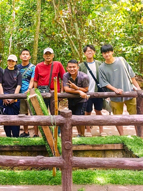 Tourists exploring booby trap at Cu Chi tunnels, Vietnam.