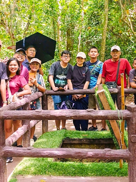 Tourists exploring booby trap at Cu Chi tunnels, Vietnam.