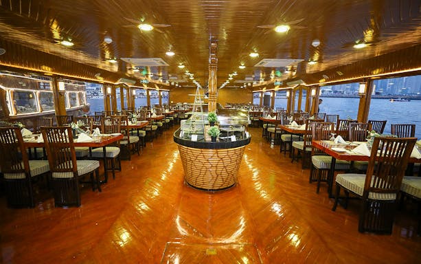 Interior of Alishba Dhow Cruise Marina with dining tables set for guests.