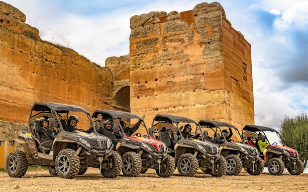 Buggy tour group in Algarve, Portugal, parked by ancient stone ruins.