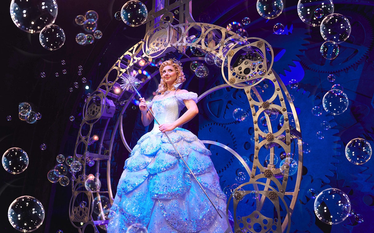 Performer in a sparkling gown on stage during a scene from Wicked musical.