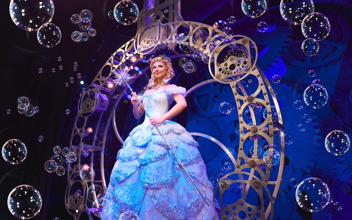 Performer in a sparkling gown on stage during a scene from Wicked musical.
