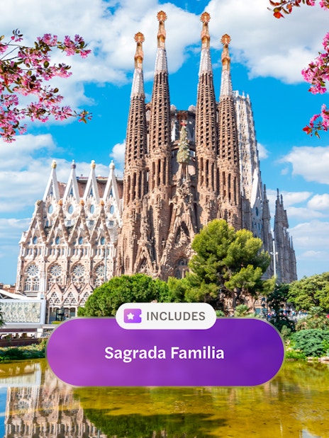 Sagrada Familia in Barcelona with blooming trees and reflection in pond.