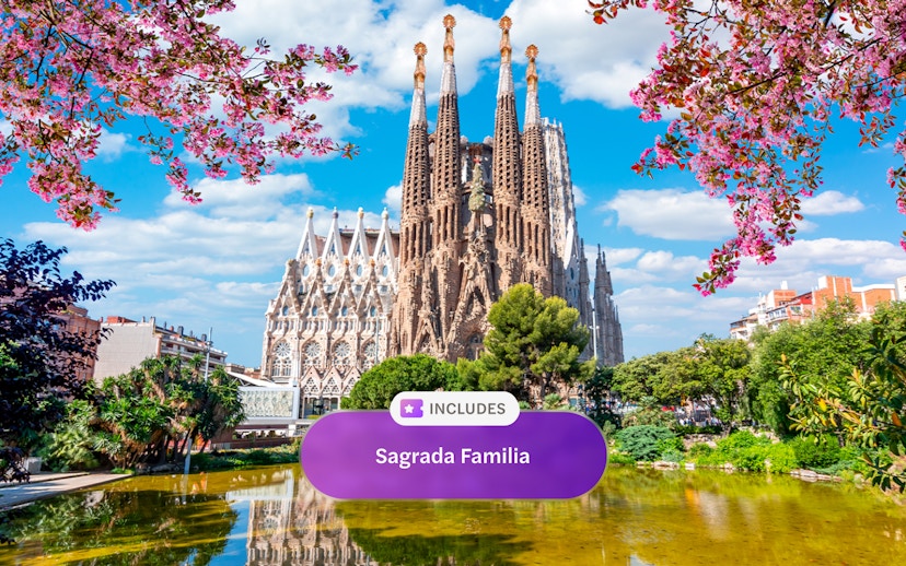 Sagrada Familia in Barcelona with blooming trees and reflection in pond.