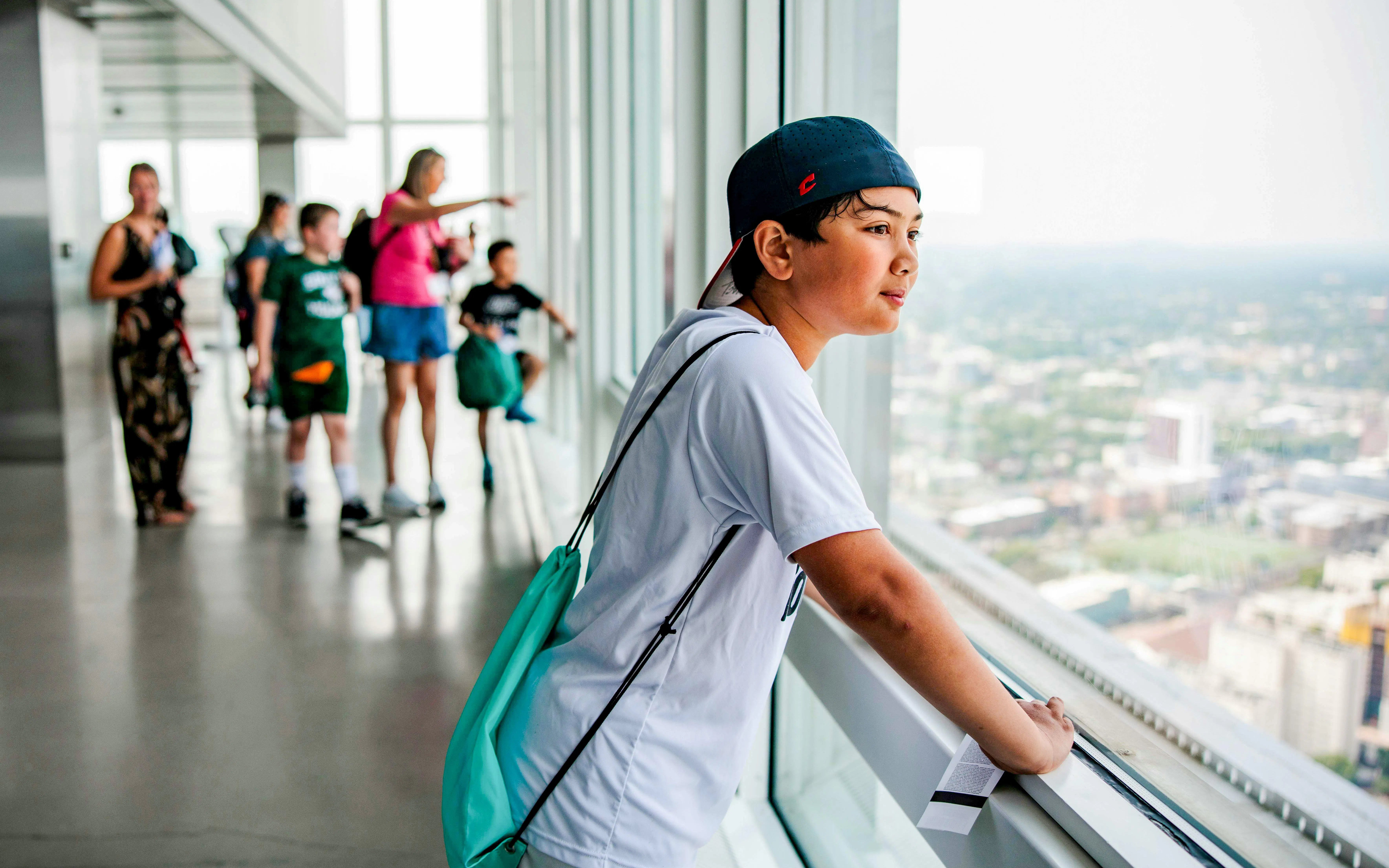 Young person looking out over Boston skyline from an observation deck.