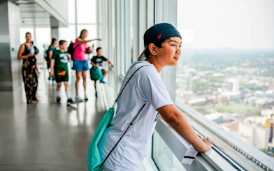 Young person looking out over Boston skyline from an observation deck.