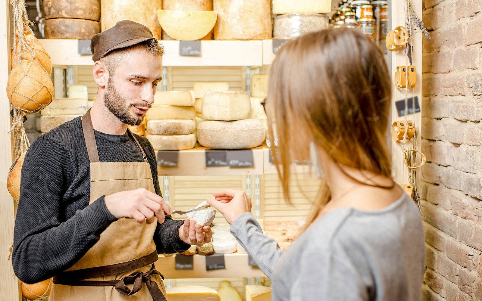Server offering cheese sample to guest in Cheese Museum, Paris.