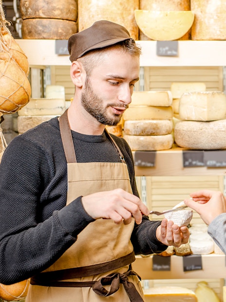 Server offering cheese sample to guest in Cheese Museum, Paris.