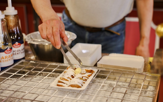 Local preparing Dutch pastries with toppings at Volendam.