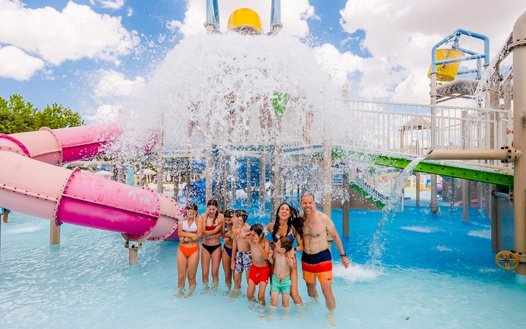 Visitors enjoying water slides and splash area at Parque Warner Beach in Madrid, Spain.
