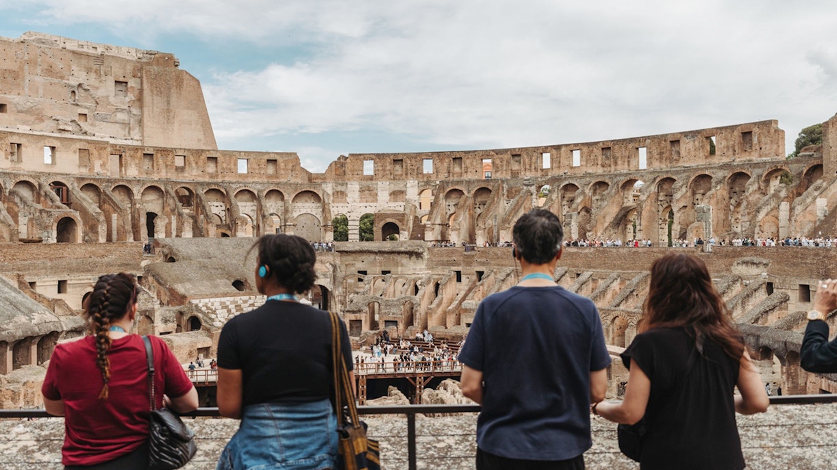Tour group with guide overlooking the interior of the Colosseum in Rome.