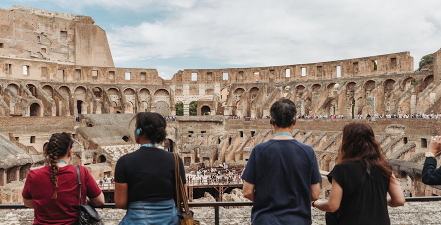Tour group with guide overlooking the interior of the Colosseum in Rome.
