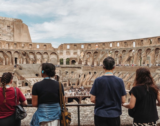 Tour group with guide overlooking the interior of the Colosseum in Rome.