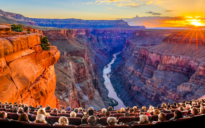 Audience watching Grand Canyon IMAX movie with canyon view and sunset.