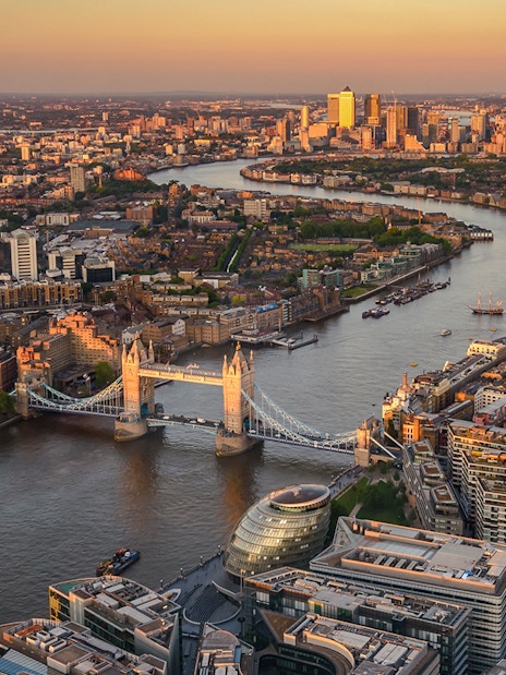 View of London from The Shard at sunset, featuring Tower Bridge and the Thames River.