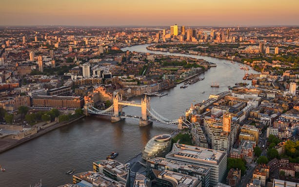 View of London from The Shard at sunset, featuring Tower Bridge and the Thames River.