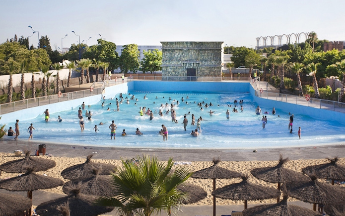 Visitors enjoying the wave pool at Agua Mágica, Isla Mágica, Seville.