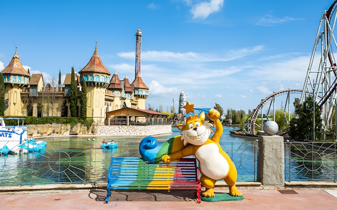 Boating on the lake with castle and roller coaster at MagicLand Amusement Park.