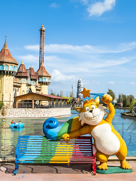 Boating on the lake with castle and roller coaster at MagicLand Amusement Park.