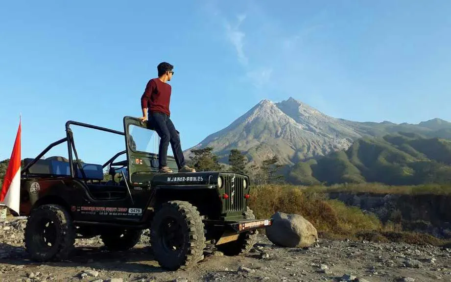 Jeep tour at sunrise near Mount Merapi, Indonesia, with a person standing on the vehicle.