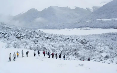 Group hiking through snowy landscape in Ushuaia with mountains in the background.