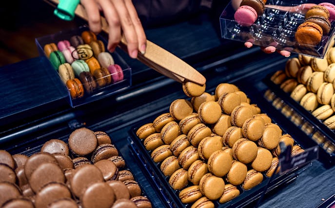Macarons being selected at a patisserie in Saint Germain, Paris food tour.