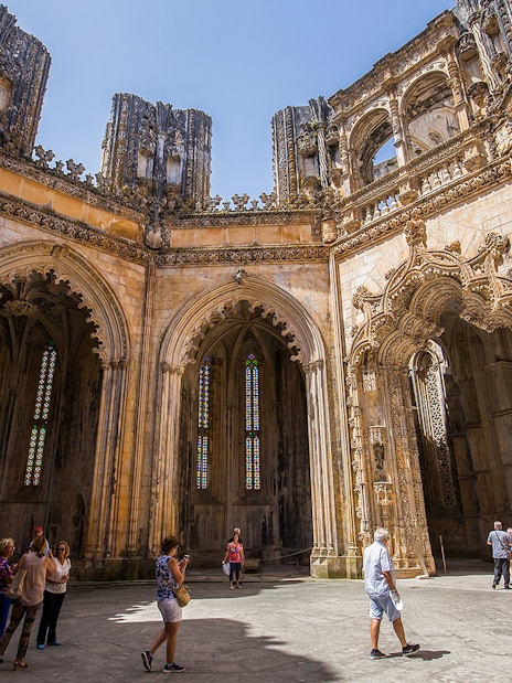 Visitors exploring the Gothic architecture of Batalha Monastery, Portugal.
