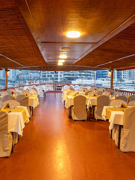 Dhow cruise dining setup with tables and chairs on Dubai Marina.