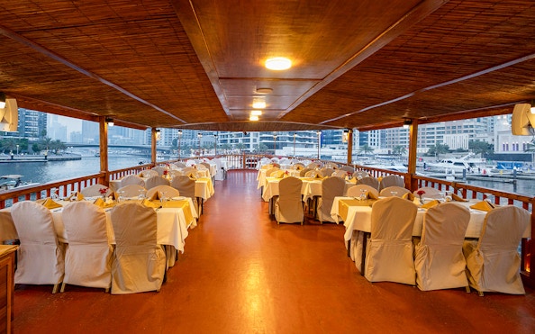 Dhow cruise dining setup with tables and chairs on Dubai Marina.