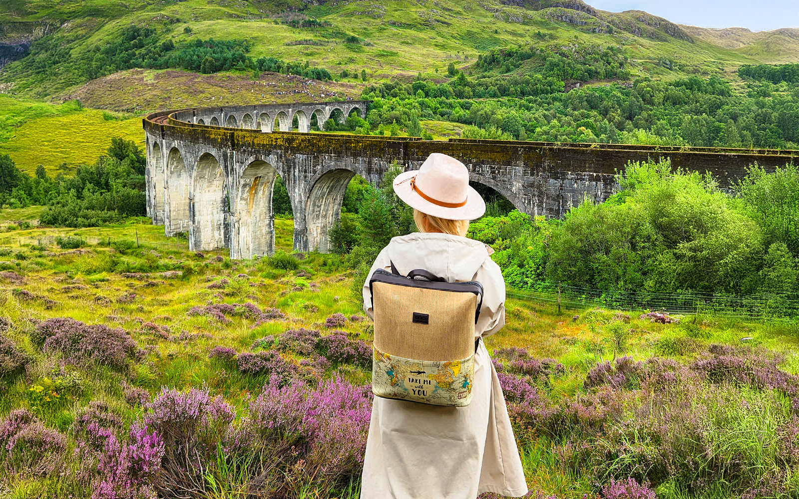 Guest standing near Glenfinnan Viaduct in Scotland, surrounded by lush greenery.