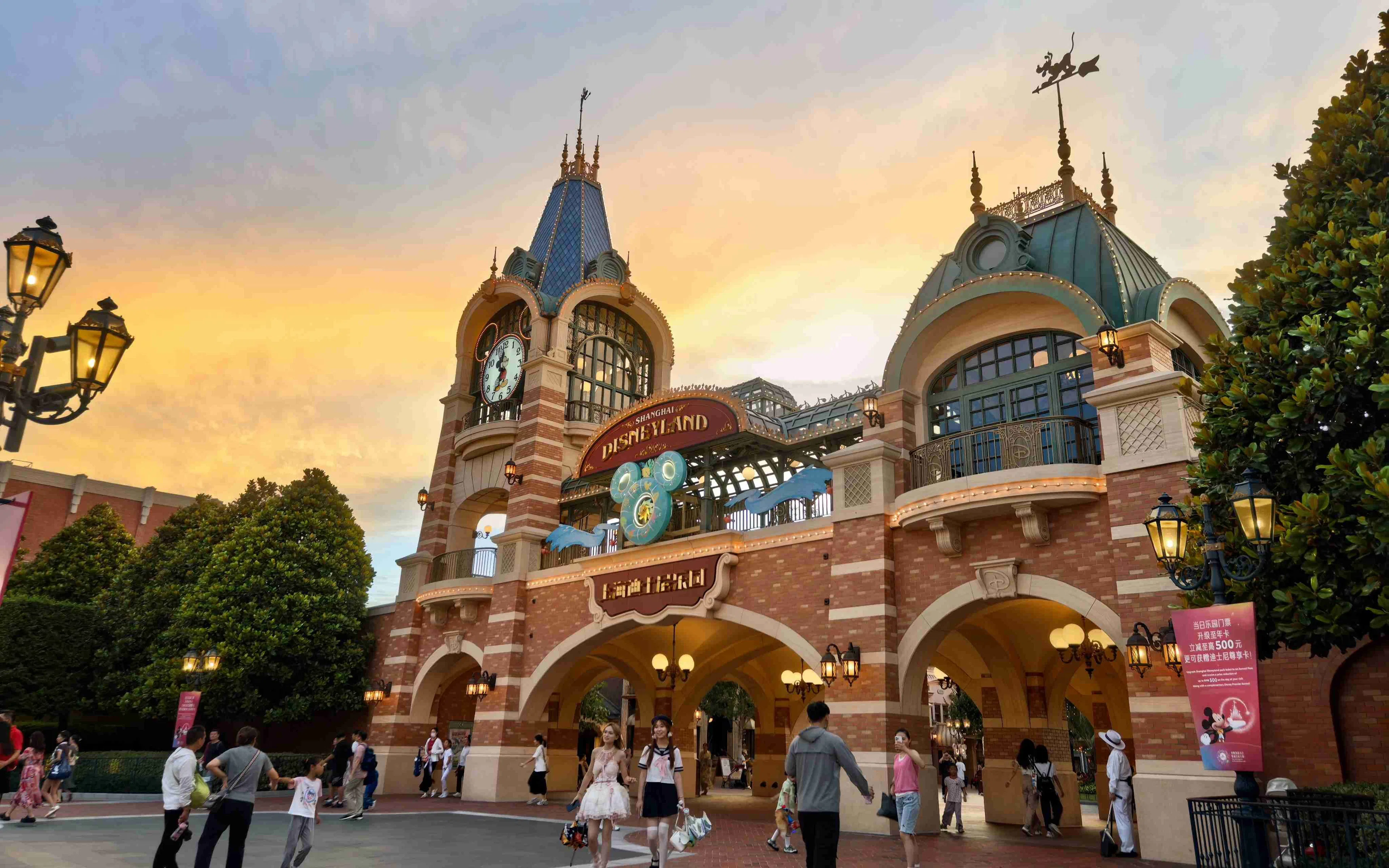 Entrance of Shanghai Disneyland with clock tower and visitors walking.