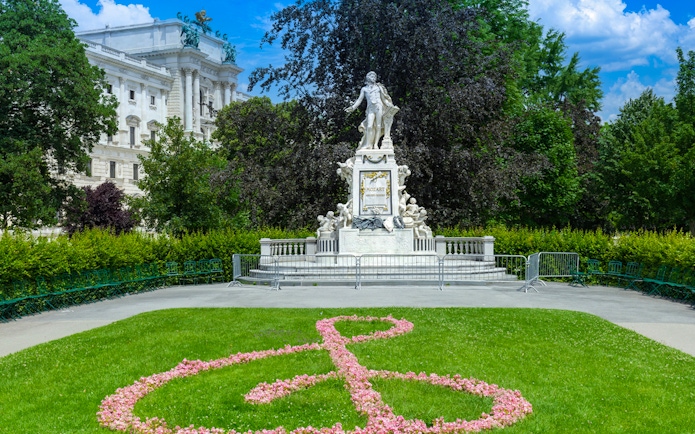 Mozart statue in the gardens of Hofburg Palace, Vienna, with floral treble clef design.