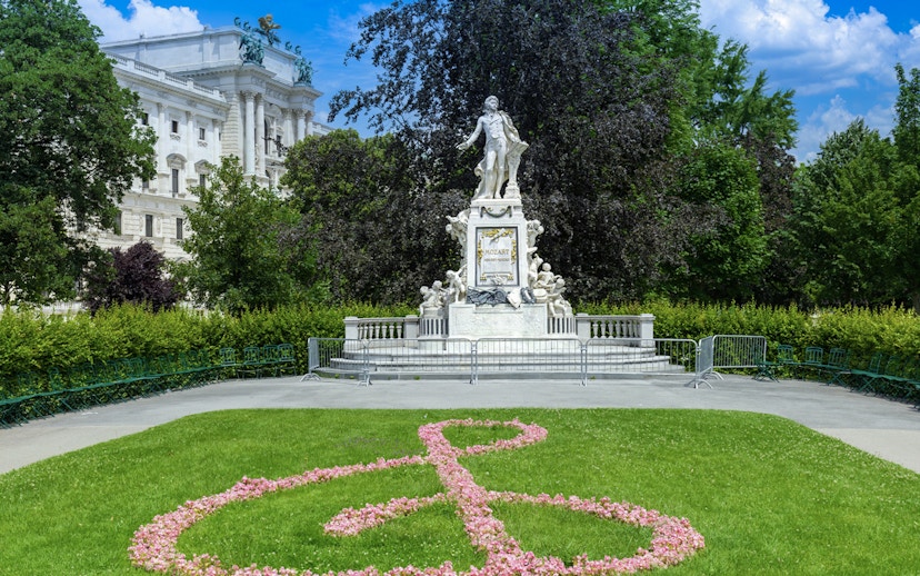 Mozart statue in the gardens of Hofburg Palace, Vienna, with floral treble clef design.