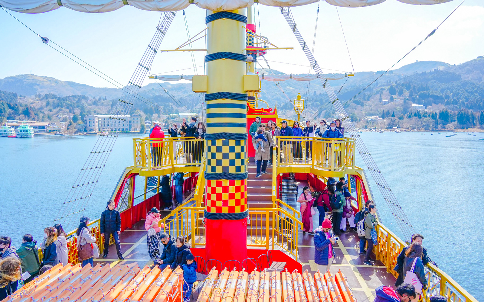 Tourists on a sightseeing cruise ship on Lake Ashi, Hakone, Japan, with scenic mountain views.