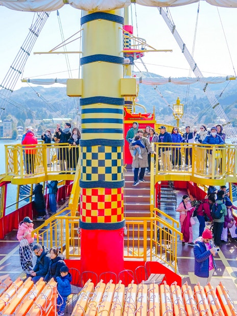 Tourists on a sightseeing cruise ship on Lake Ashi, Hakone, Japan, with scenic mountain views.