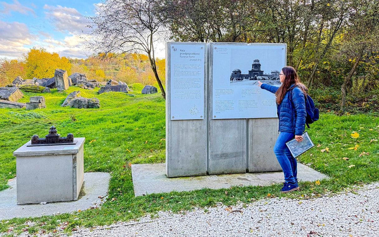 Tour guide explaining historical information at Płaszów Concentration Camp memorial site.