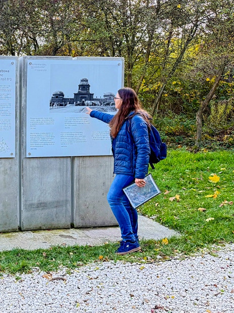 Tour guide explaining historical information at Płaszów Concentration Camp memorial site.